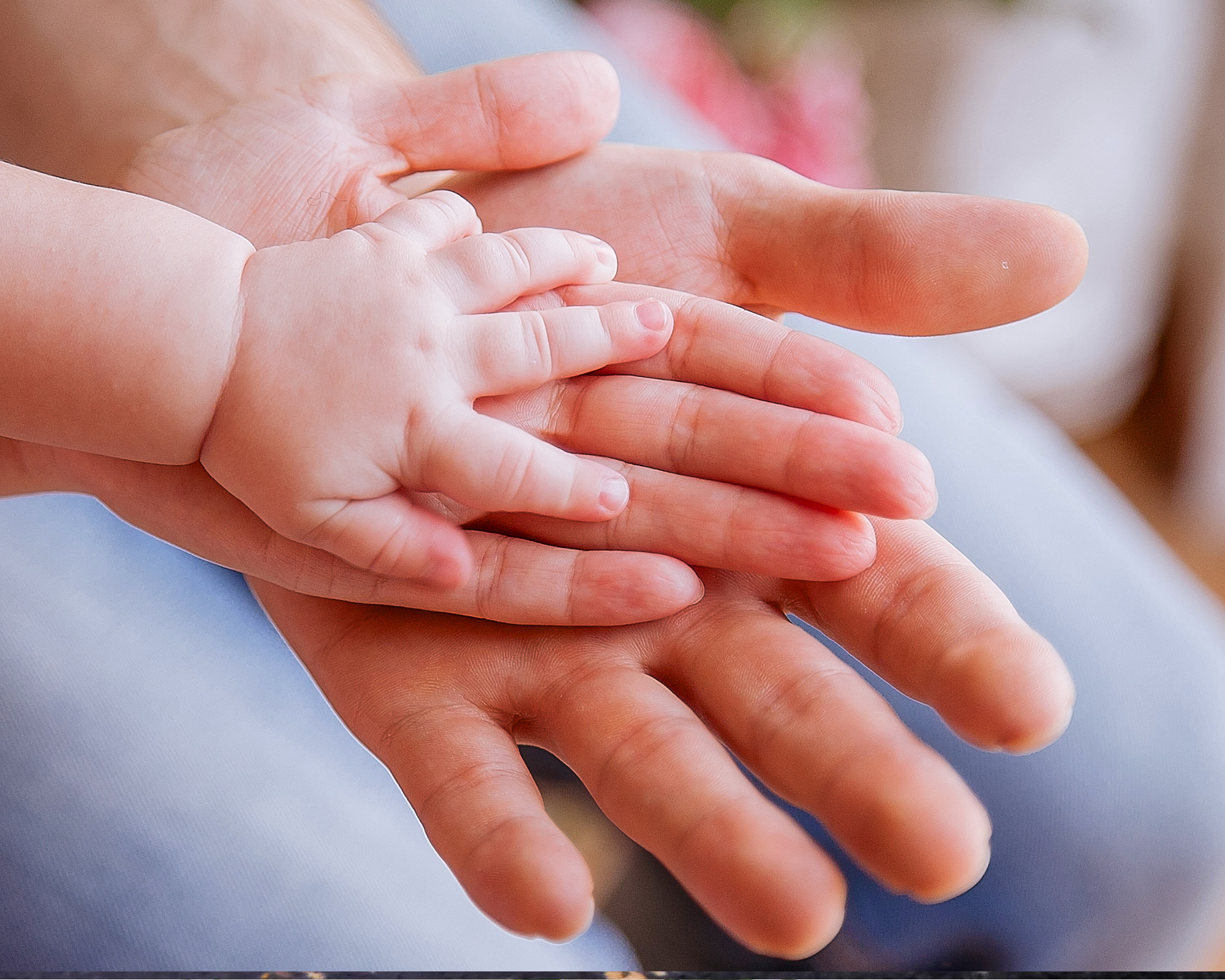 Family hands holding baby's hand